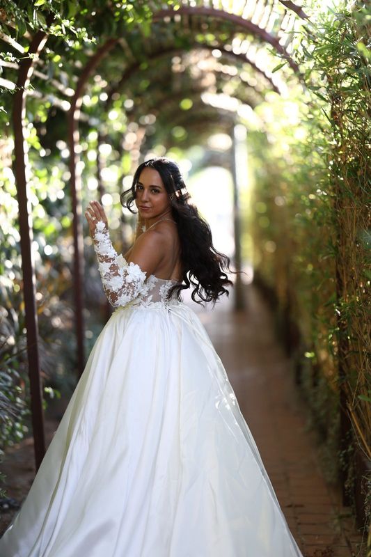 White wedding ball gown with floral sleeves in a garden