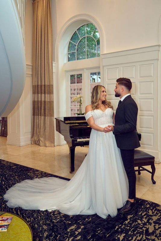Off-shoulder bridal gown beside a grand piano